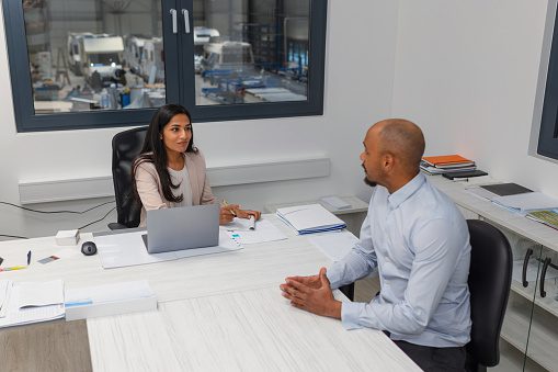 Job interview in an office, an Indian female manager discussing with a motivated African American male candidate.